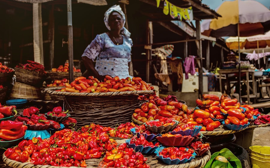 Vendeuse sur un marché ouest-africain devant ses étals de piments et de tomates